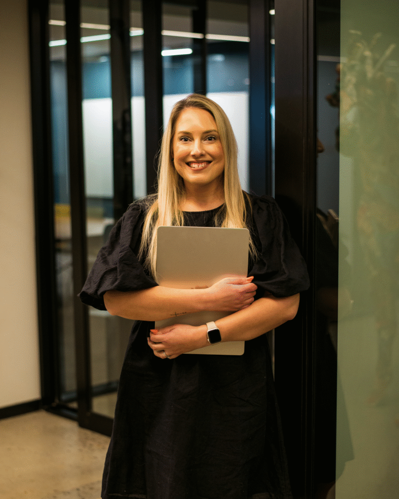 Smiling woman with laptop at cozy workspace.